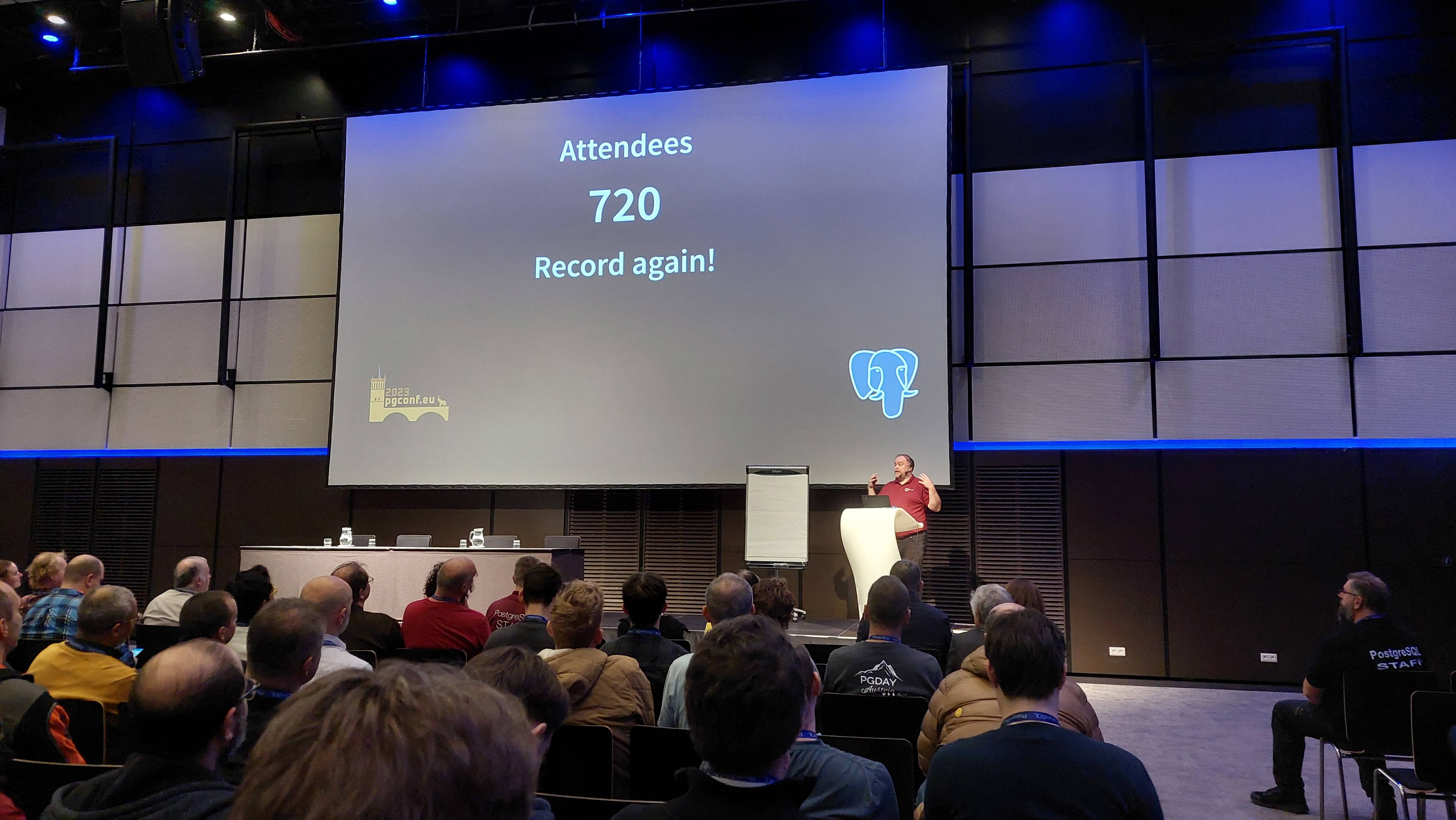Magnus Hagander presenting a slide that shows 720 registrations